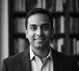 John, Founder of Readalike Finder, smiling in front of bookshelves.